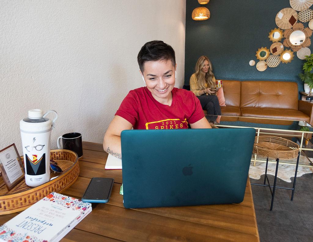 Woman smiling at laptop with Granite City Workspaces lounge visible in background